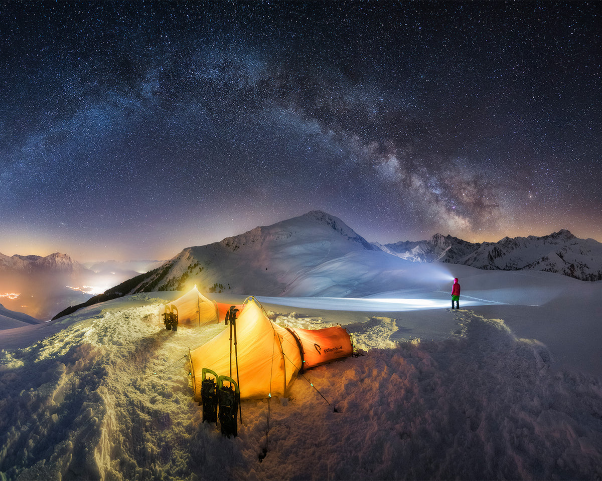 Snow camp under the Milky Way, a person lighting across the snowfield with the Betty BT