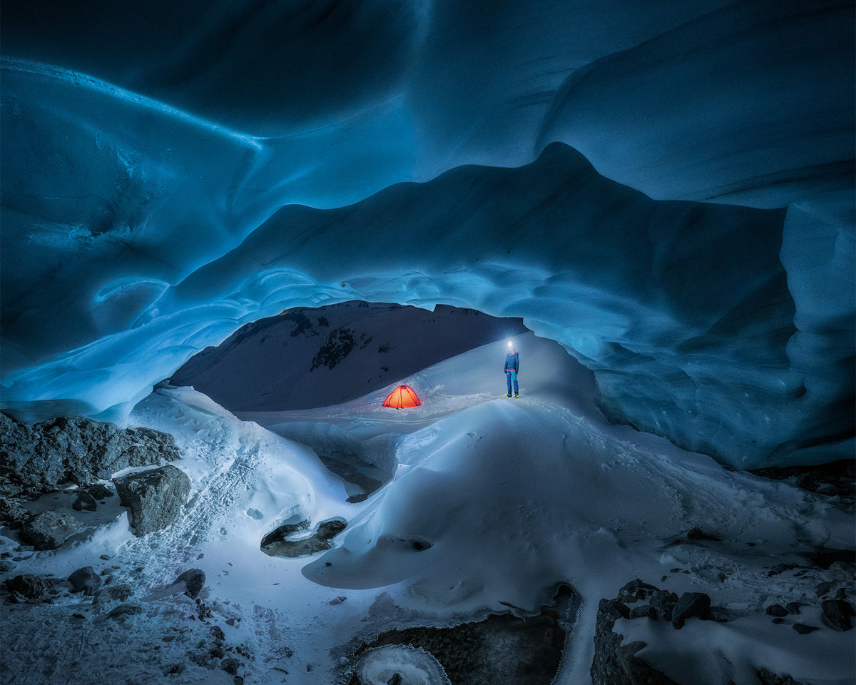 Person with the Betty BT in an ice cave, an illuminated tent in the background