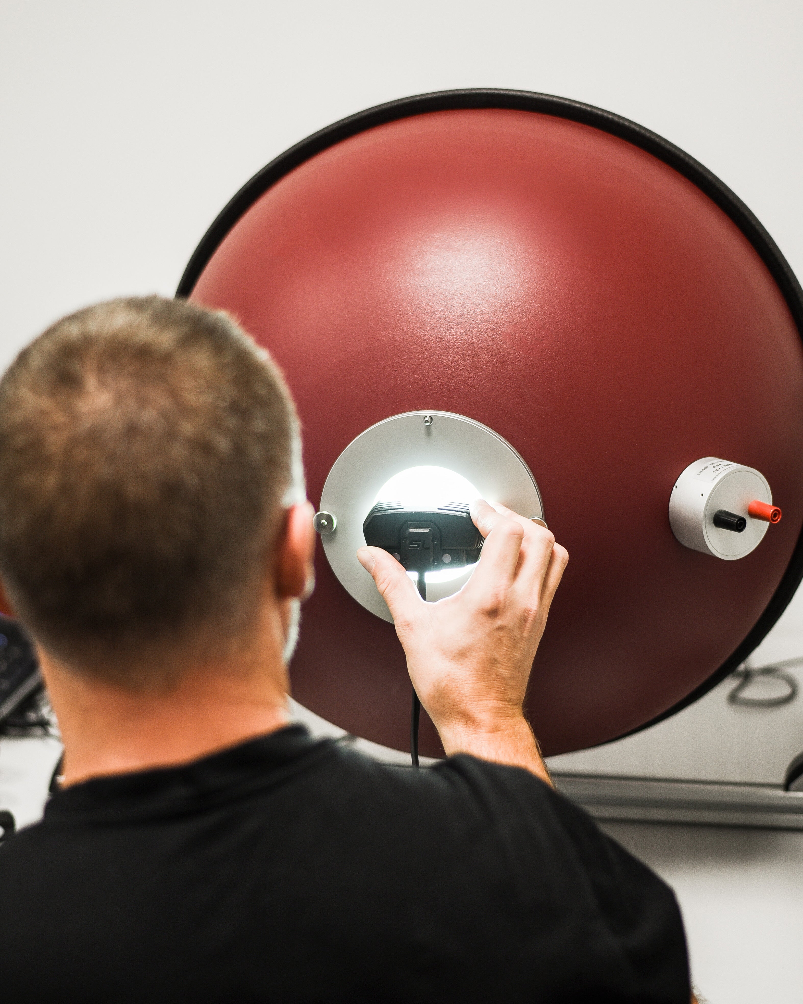 person inspects a red Lupine light