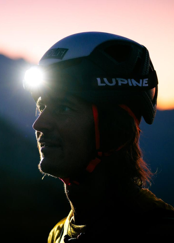 Person with a Lupine headlamp backlit at sunset
