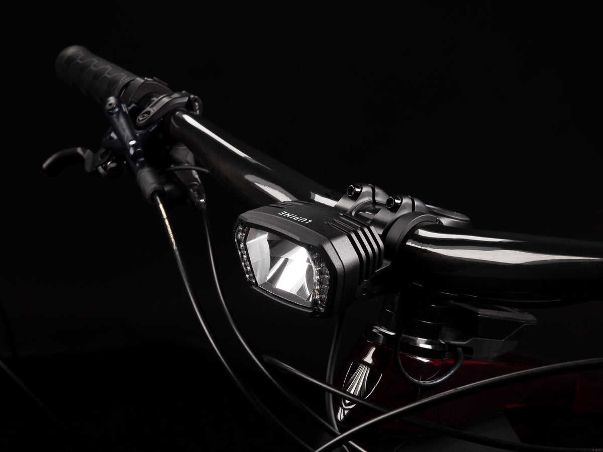 SL X am Lenker eines E-Bikes vor dunklem Hintergrund